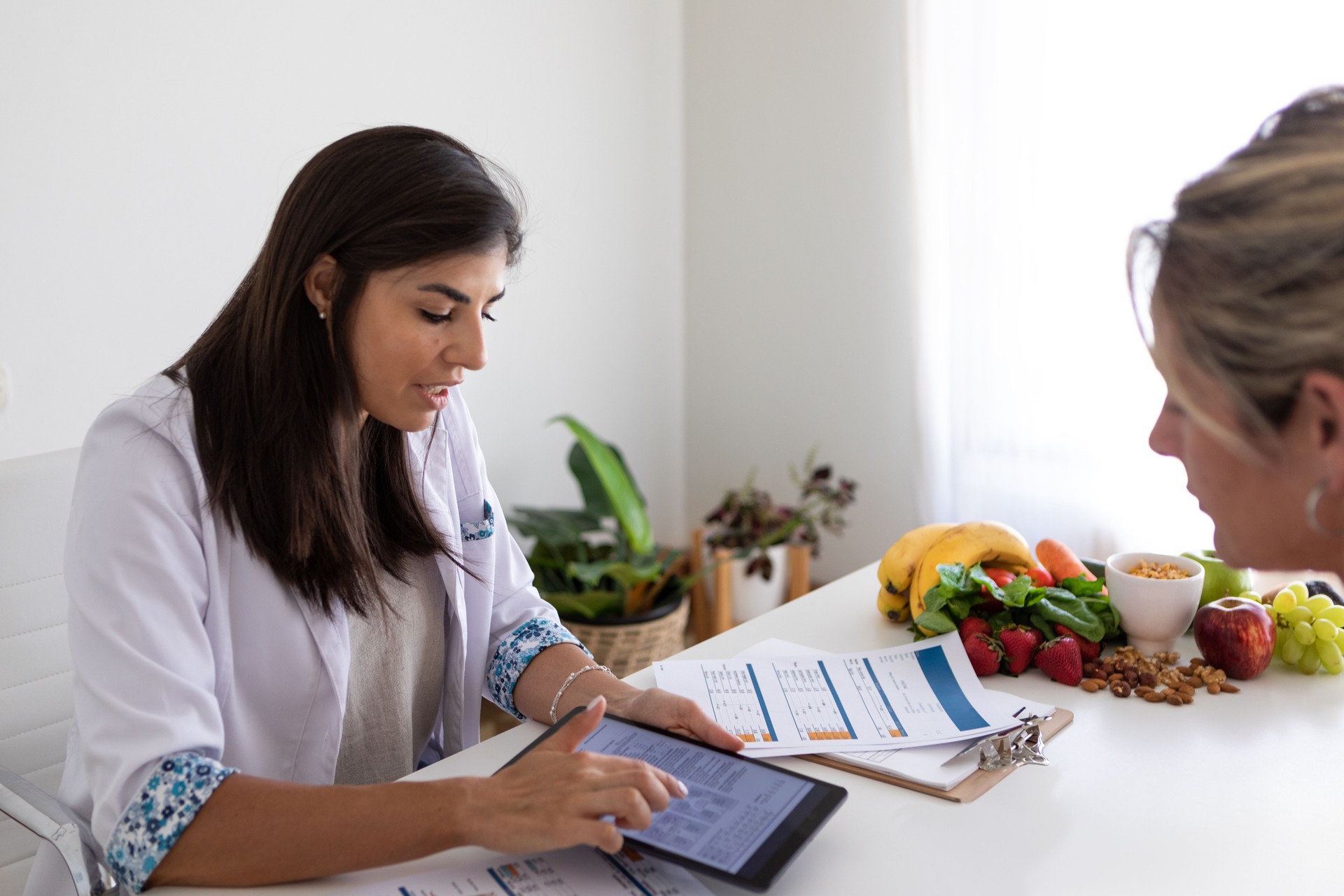 Ernährungsärztin und Deportologin im Büro ihres Schreibtisches während einer medizinischen Konsultation mit einer jungen Patientin