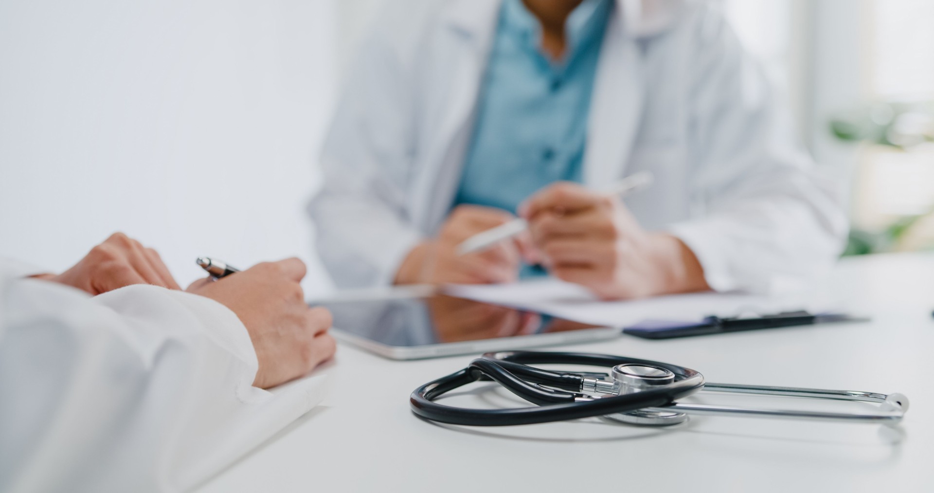 Close up of mature Asian man doctors and young woman doctors discussing over medical report in meeting room at health clinic.